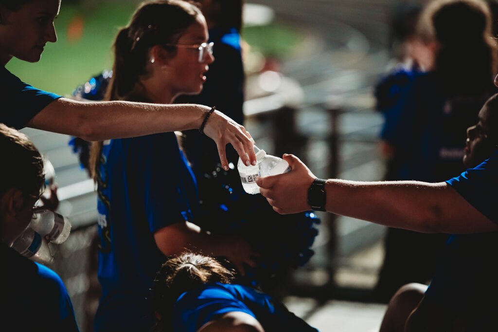 Volunteer passes out water to band students